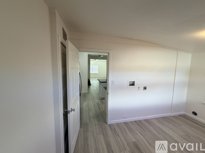 A hallway with a door on the left and a bathroom on the right.
