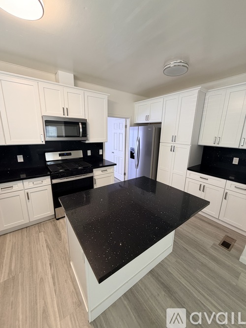 A kitchen with black countertops and white cabinets.