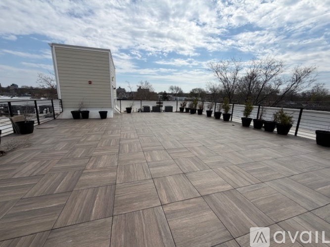 A wooden deck with a white building and potted plants in the background.