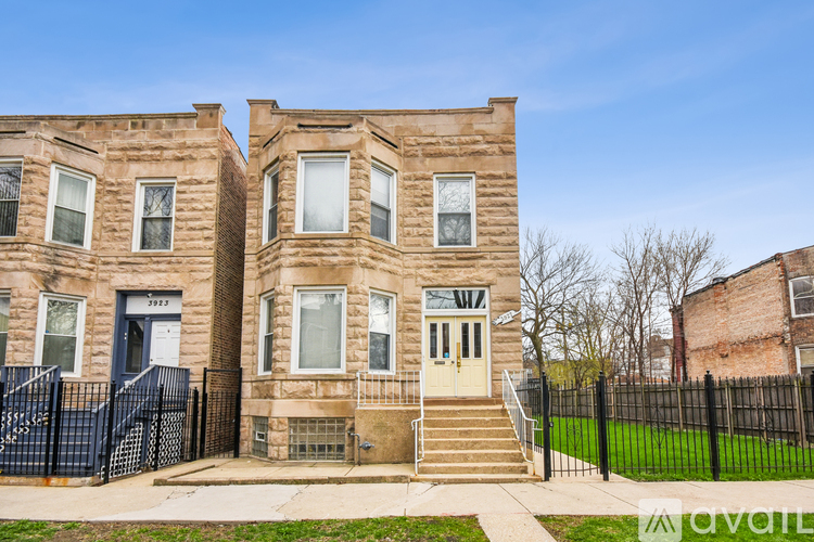 A row of brown brick townhouses with a black fence in front.