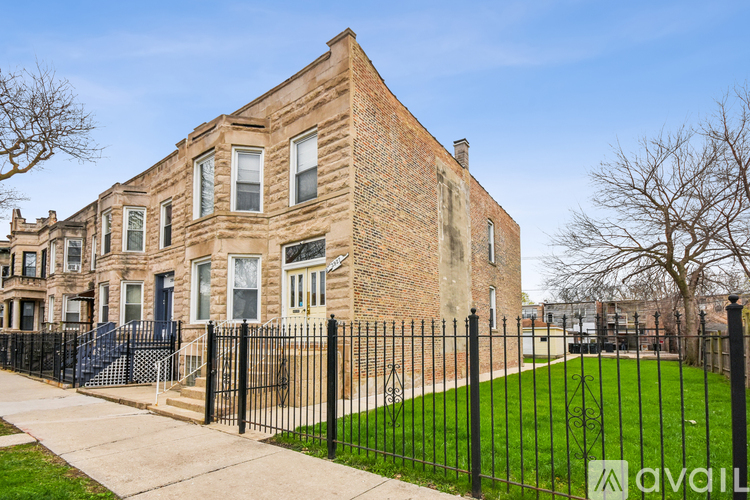 A brick house with a black fence in front.