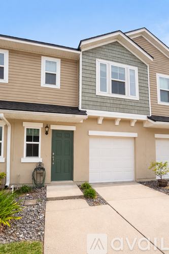 A two-story house with a green door and white garage door.