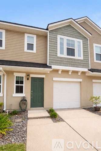A two-story house with a green door and white garage door.