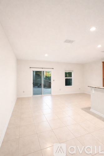 A spacious room with a tiled floor and a glass door leading to a balcony.