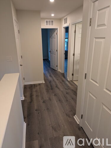 A hallway with wood flooring and white walls.