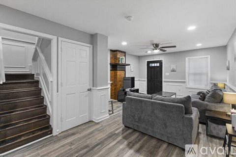 A living room with a grey couch and a staircase.