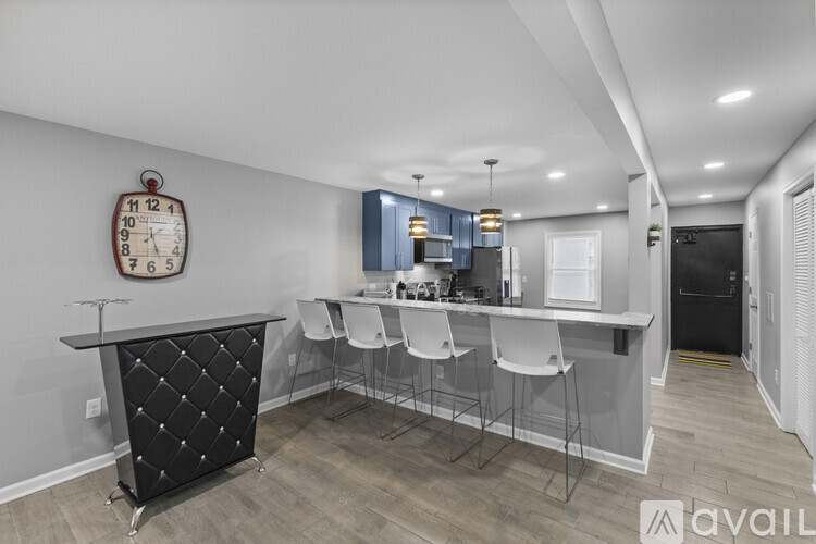 A kitchen with a black counter and white chairs.