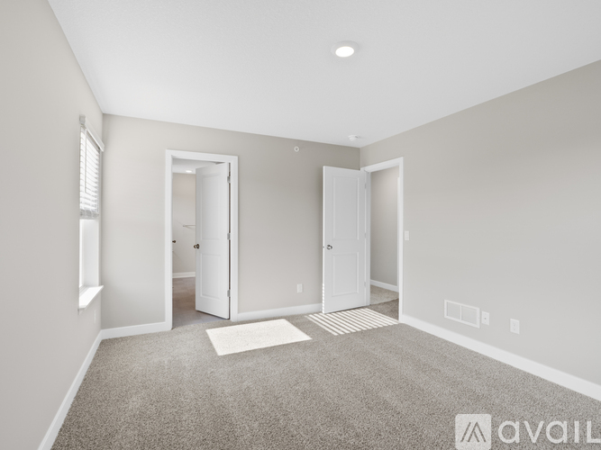 A spacious room with two doors and a carpeted floor.