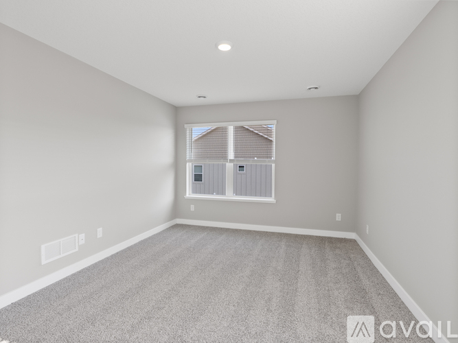 A spacious room with a carpeted floor and a window with blinds.