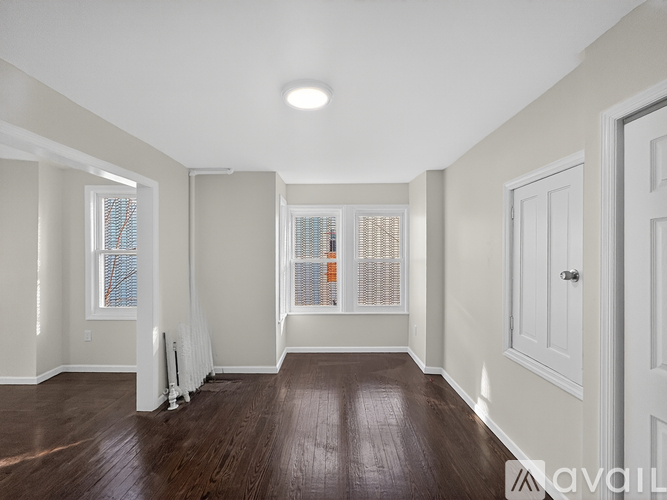 A spacious room with wooden floors and white walls.