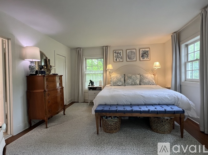 A bedroom with a bed, nightstand, and a wooden dresser.