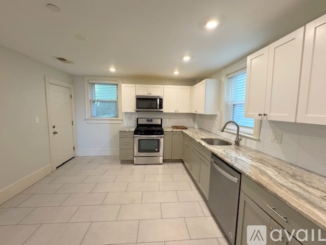 A kitchen with white cabinets and a marble countertop.
