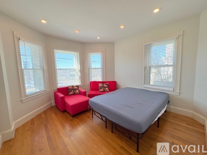 A bedroom with a bed, a chair, and a window.