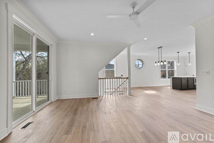 A spacious room with wooden flooring and a staircase with a metal railing.