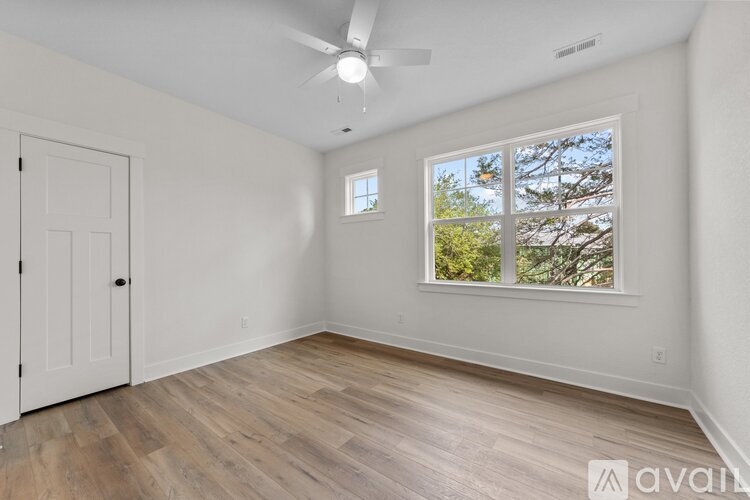A room with a ceiling fan and a window with a view of trees.