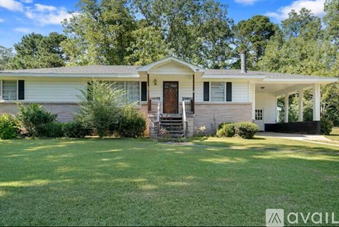 A house with a front yard and a tree in the background.