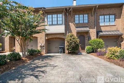A large, two-story house with a driveway in front.