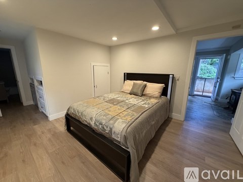 A bedroom with a large bed and wooden flooring.