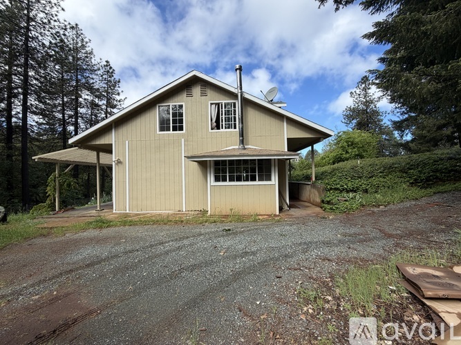 A house with a brown roof and a gravel driveway in front of it.