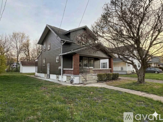 A house with a grey roof and a tree in front of it.