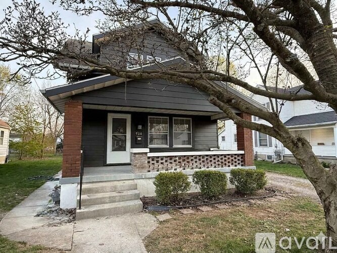 A house with a front porch and a tree in front.