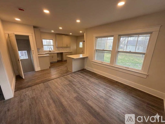 A spacious room with wooden flooring and large windows.