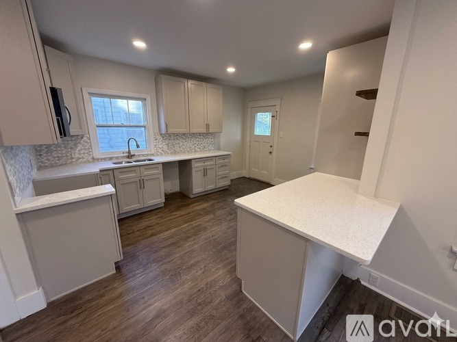 A kitchen with white cabinets and a wooden floor.