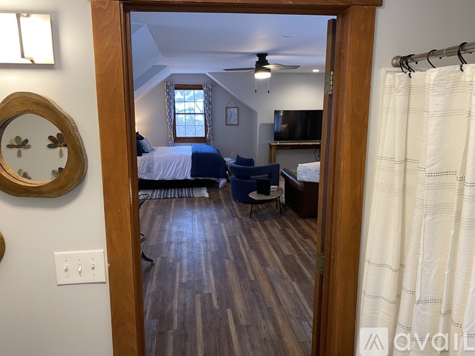 A bedroom with a bed, a chair, and a ceiling fan.