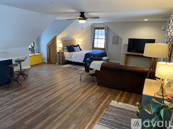 A bedroom with a bed, a couch, a TV, and a ceiling fan.