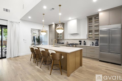 A modern kitchen with wooden chairs and a center island.