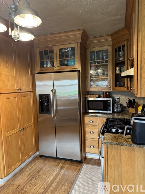 A kitchen with wooden cabinets and a stainless steel refrigerator.