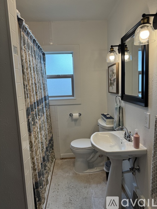 A bathroom with a toilet, sink, and shower.