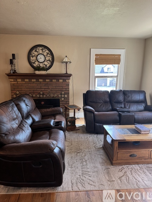 A living room with a black leather couch and a wooden coffee table.