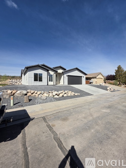 A modern house with a stone wall and a gravel driveway in front.