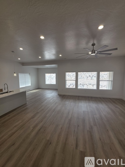 A spacious room with wooden flooring and a ceiling fan.