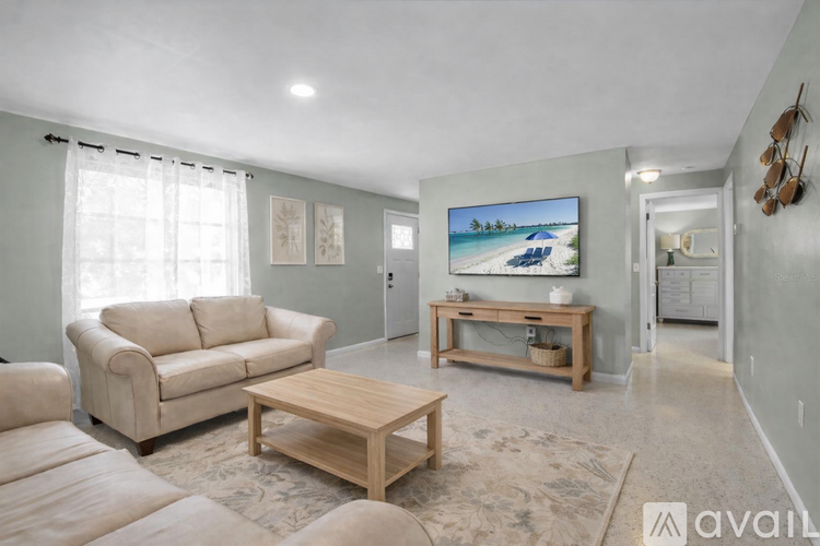 A living room with a couch, a coffee table, and a painting of a beach scene on the wall.