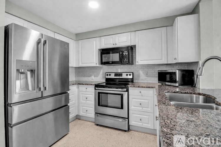 A kitchen with a stainless steel refrigerator and a microwave above the stove.
