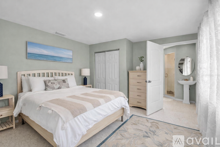 A bedroom with a large bed, a dresser, and a mirror.
