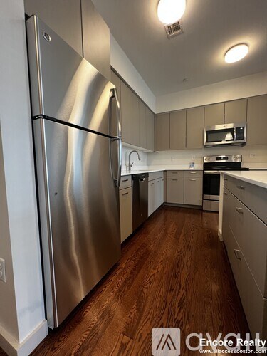 A kitchen with a stainless steel refrigerator and wooden floors.