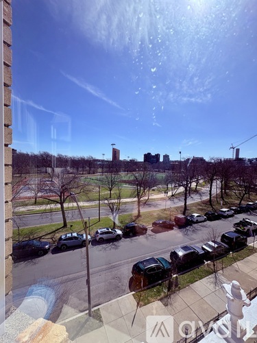 A view from a window looking out at a street with cars and buildings.