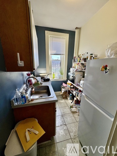 A kitchen with a sink, refrigerator, and a window.