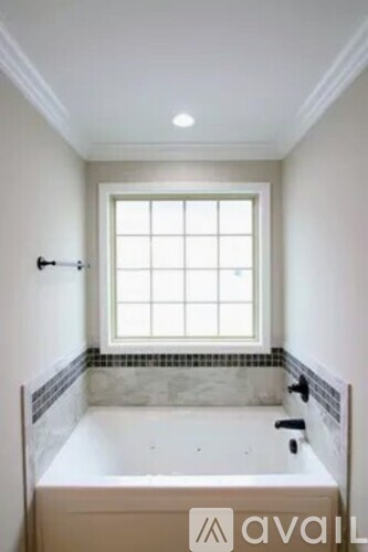 A white bathroom with a tub and a window.