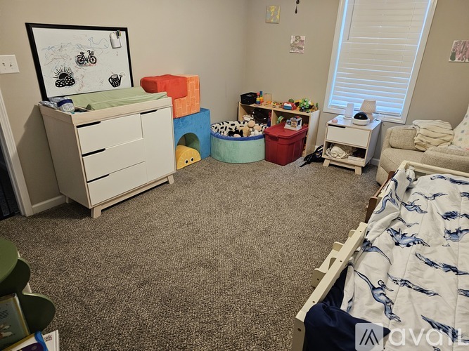 A child's bedroom with a bed, dresser, and toys.