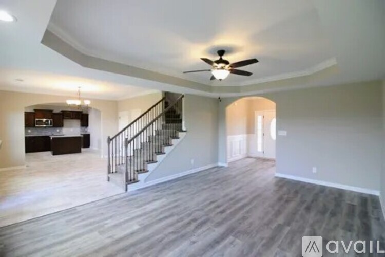 A spacious living room with a staircase and a ceiling fan.