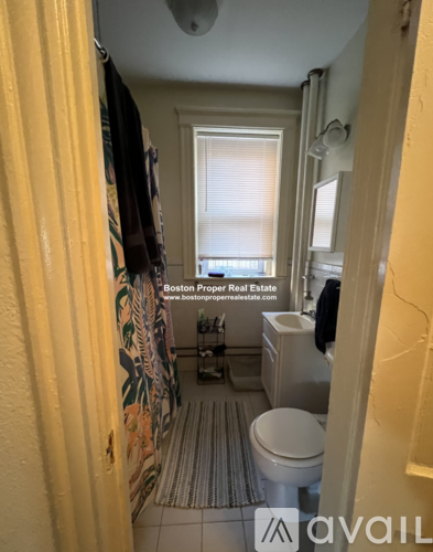 A bathroom with a toilet, sink, and shower curtain.
