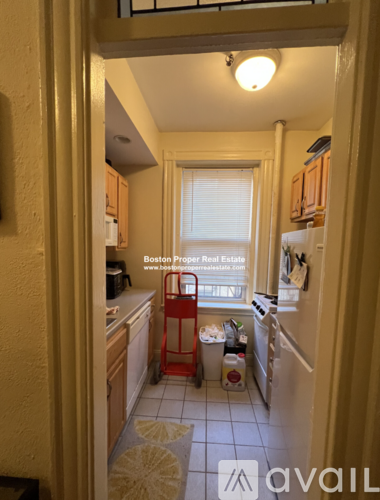 A kitchen with a red shopping cart in the middle of it.