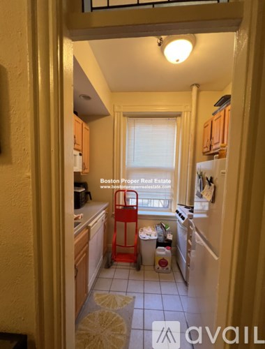 A kitchen with a red shopping cart in the middle of it.