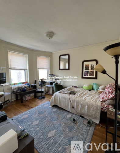 A bedroom with a bed, a desk, and a chair.