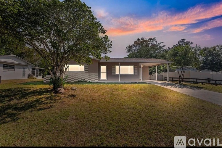A modern house with a large front yard and a tree in the foreground.