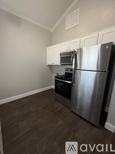 A kitchen with a stainless steel refrigerator and wooden flooring.